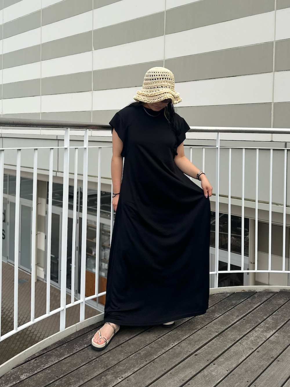 ブラック系のワンピース、ベージュ系のサンダル、ベージュ系のハットを着用したレディースの夏コーディネートの2枚目の写真