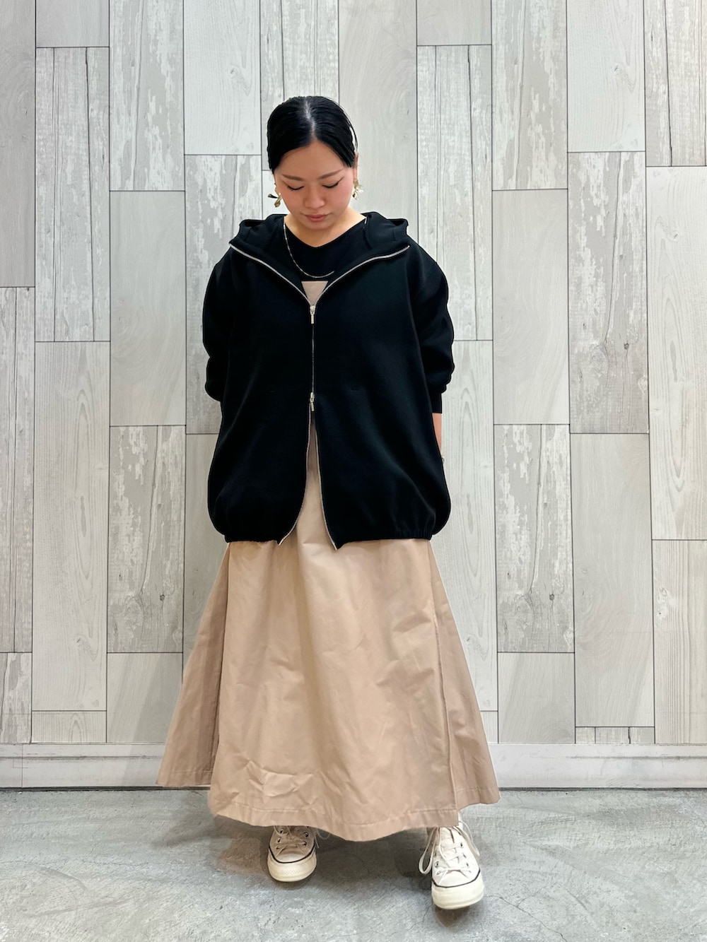 ベージュ系のワンピース、ブラック系のパーカー、ホワイト系のスニーカーを着用したレディースの冬コーディネートの3枚目の写真