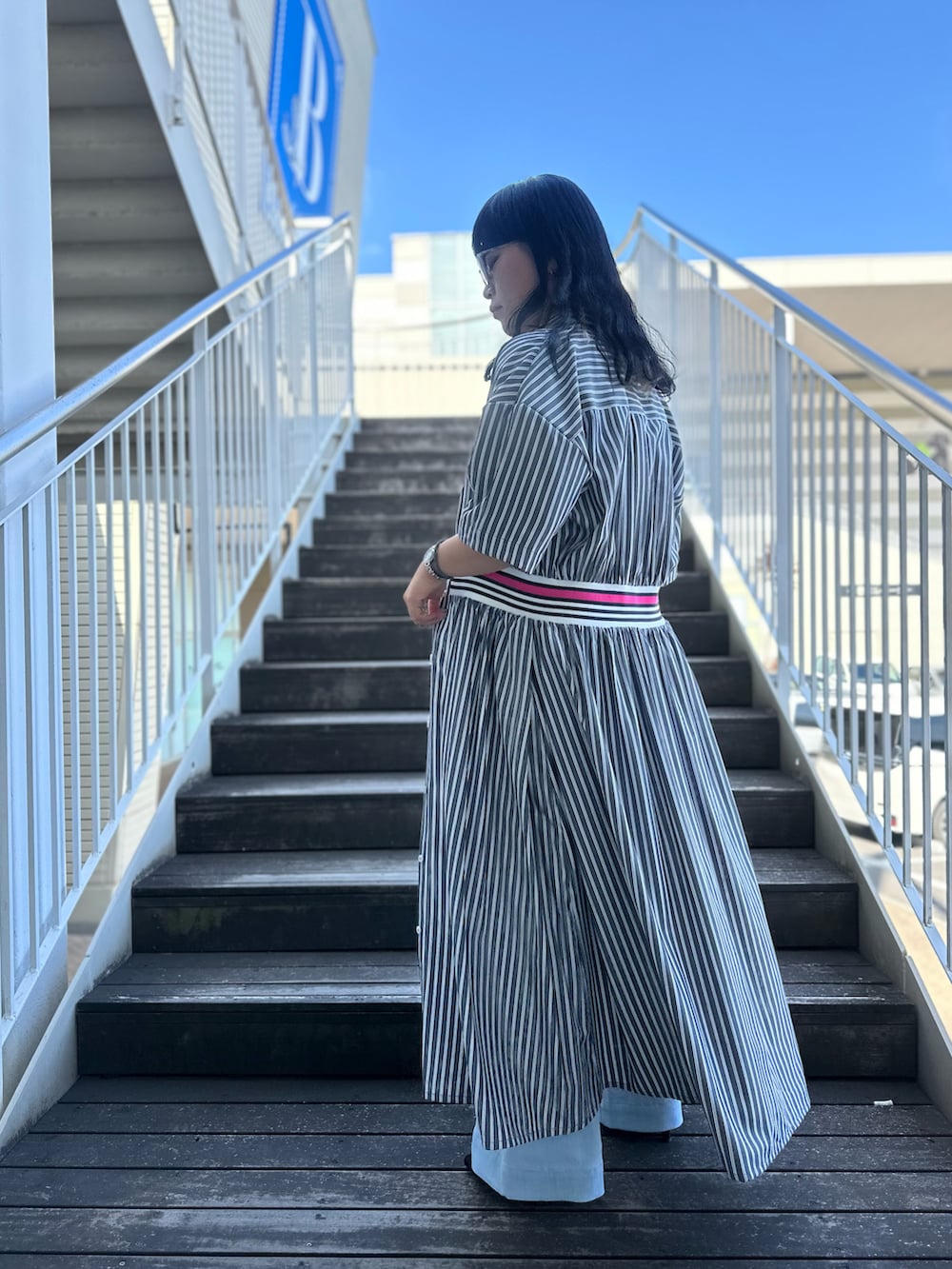 ブラック系のワンピース、ブルー系のデニムパンツを着用したレディースの春コーディネートの5枚目の写真