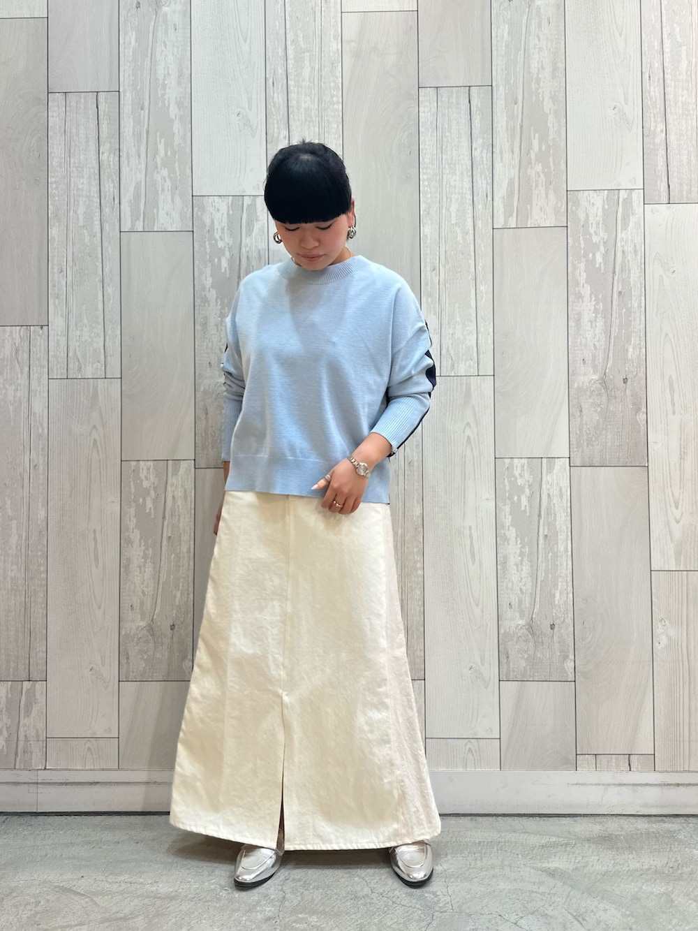 ブルー系のニット/セーター、ホワイト系のデニムスカート、シルバー系のローファーを着用したレディースの冬コーディネートの3枚目の写真