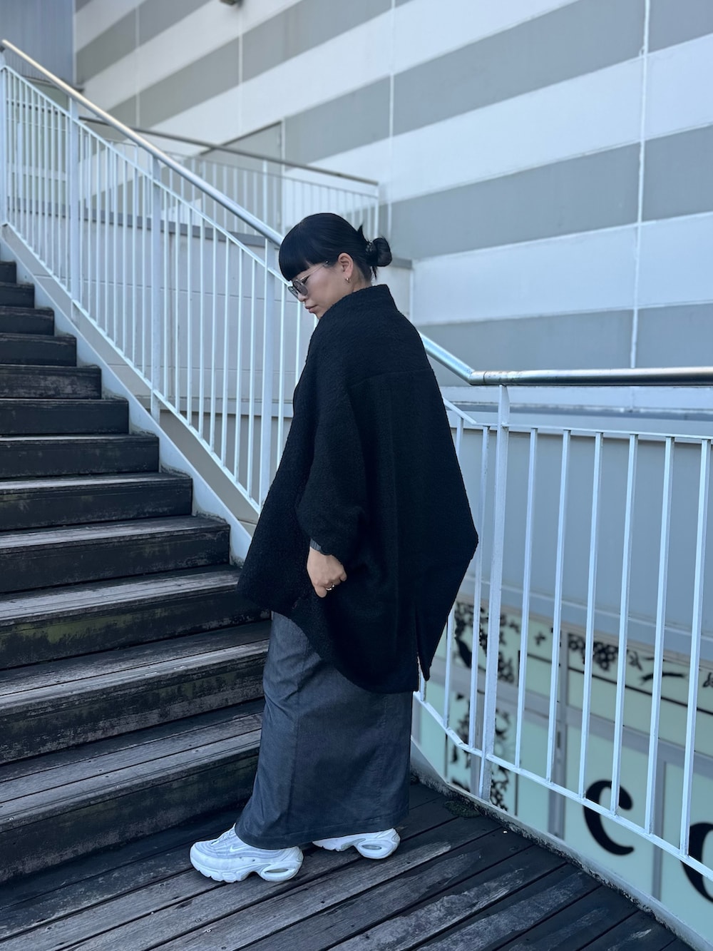 ブラック系のTシャツ/カットソー、グレー系のスカート、ホワイト系のスニーカーを着用したレディースの秋コーディネートの4枚目の写真