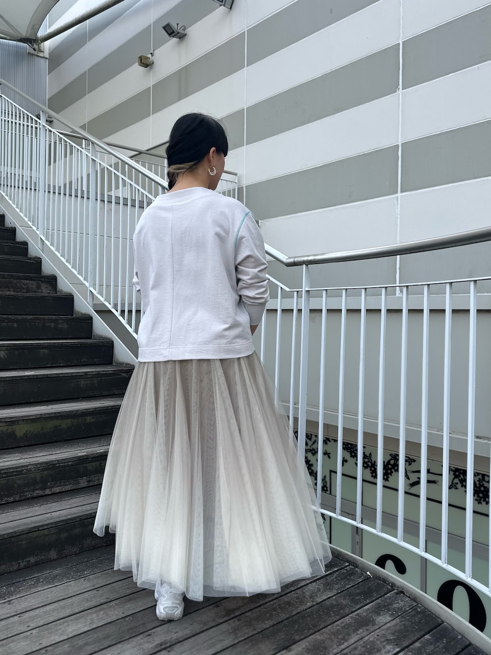 グレー系のカーディガン/ボレロ、ベージュ系のスカート、ホワイト系のスニーカーを着用したレディースの冬コーディネートの4枚目の写真