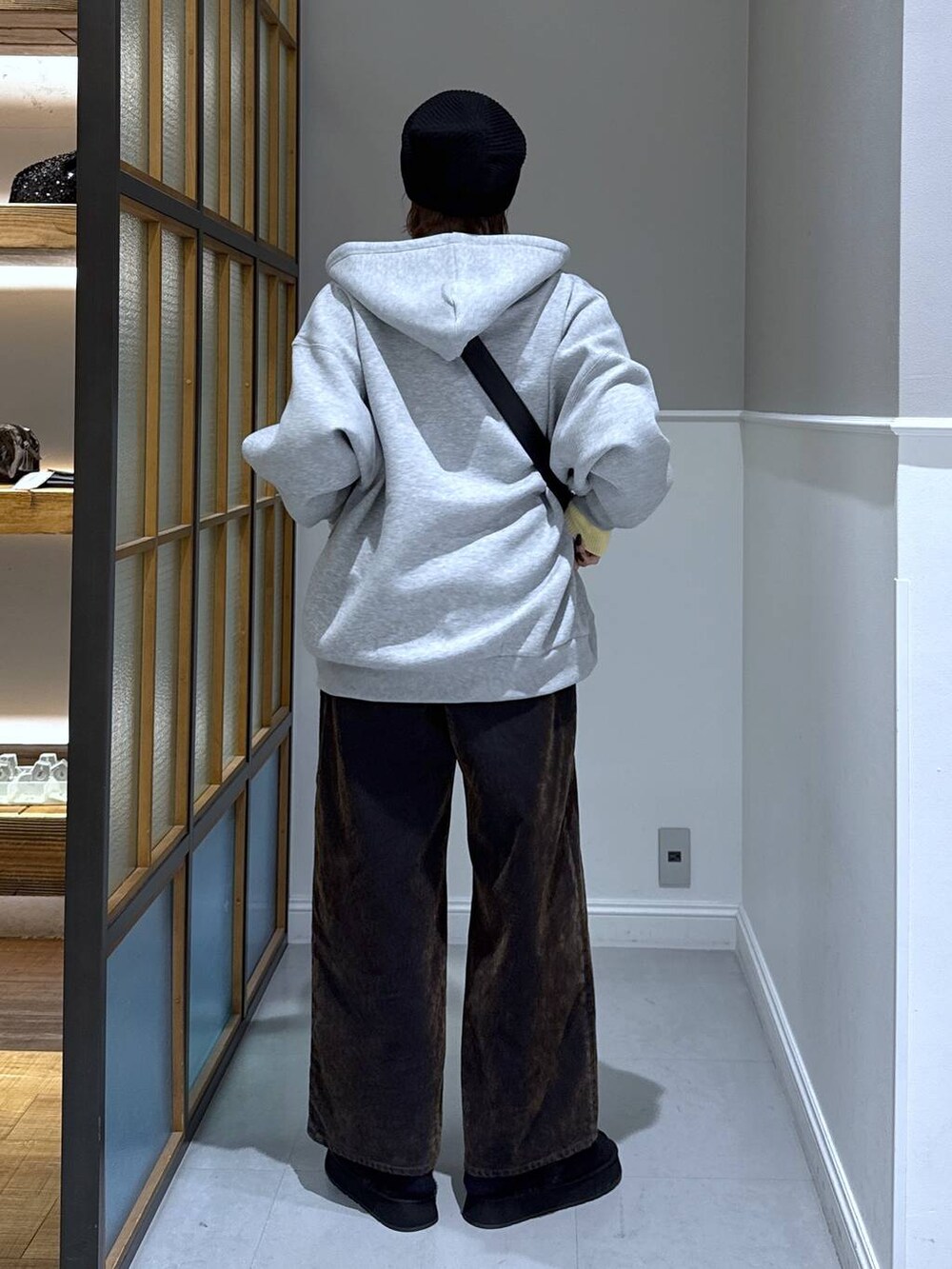 ブラック系のニット/セーター、ブラック系のショルダーバッグ、グレー系のパーカーを着用したレディースの冬コーディネートの2枚目の写真