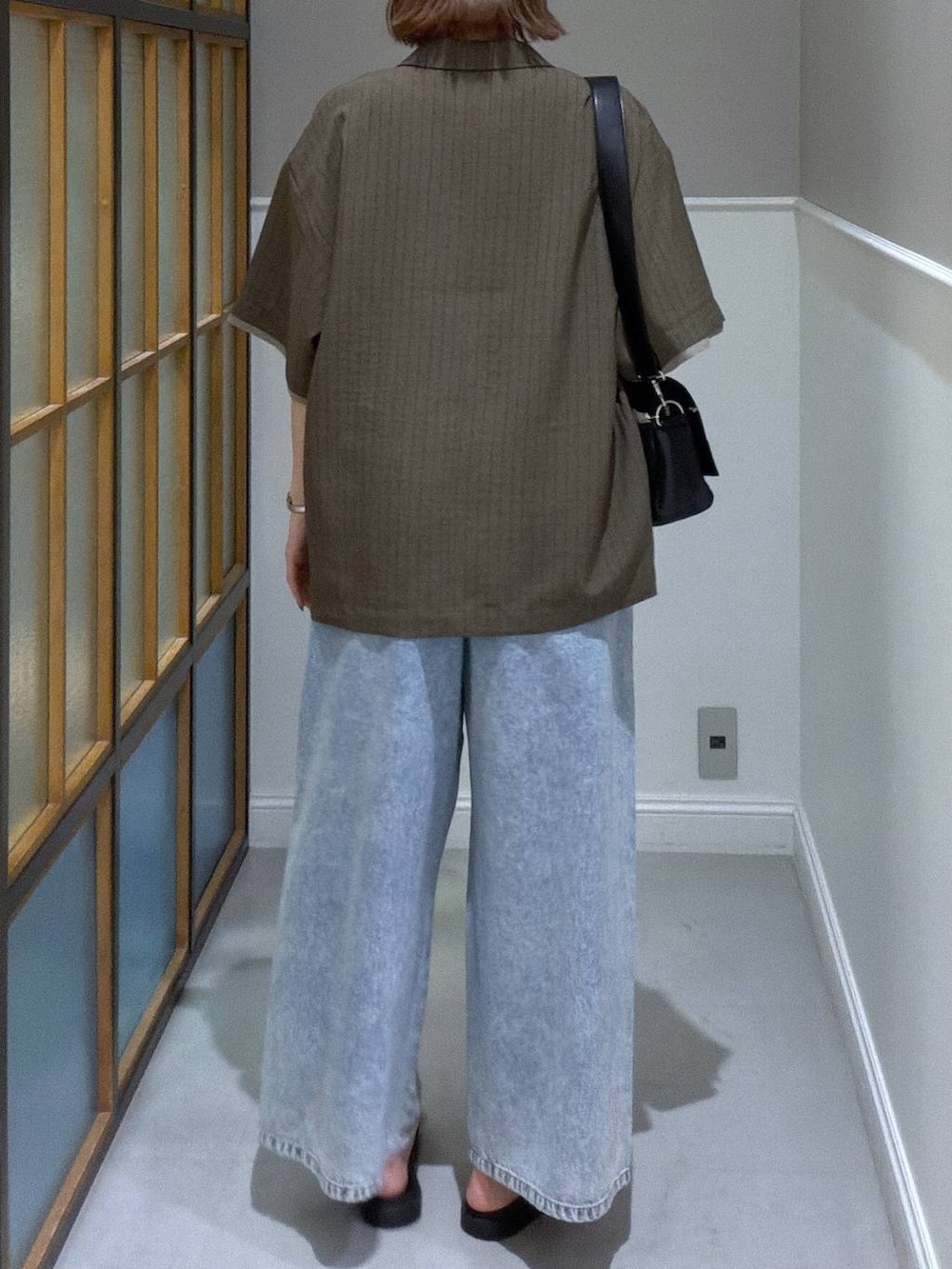 ブラック系のショルダーバッグ、ブルー系のデニムパンツ、ブラック系のサンダルを着用したレディースの春コーディネートの2枚目の写真