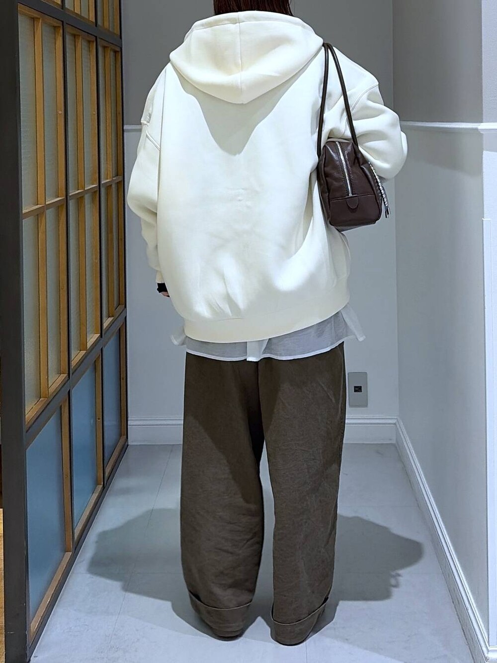 ホワイト系のTシャツ/カットソー、ホワイト系のパーカー、グレー系のニット/セーターを着用したレディースの冬コーディネートの3枚目の写真