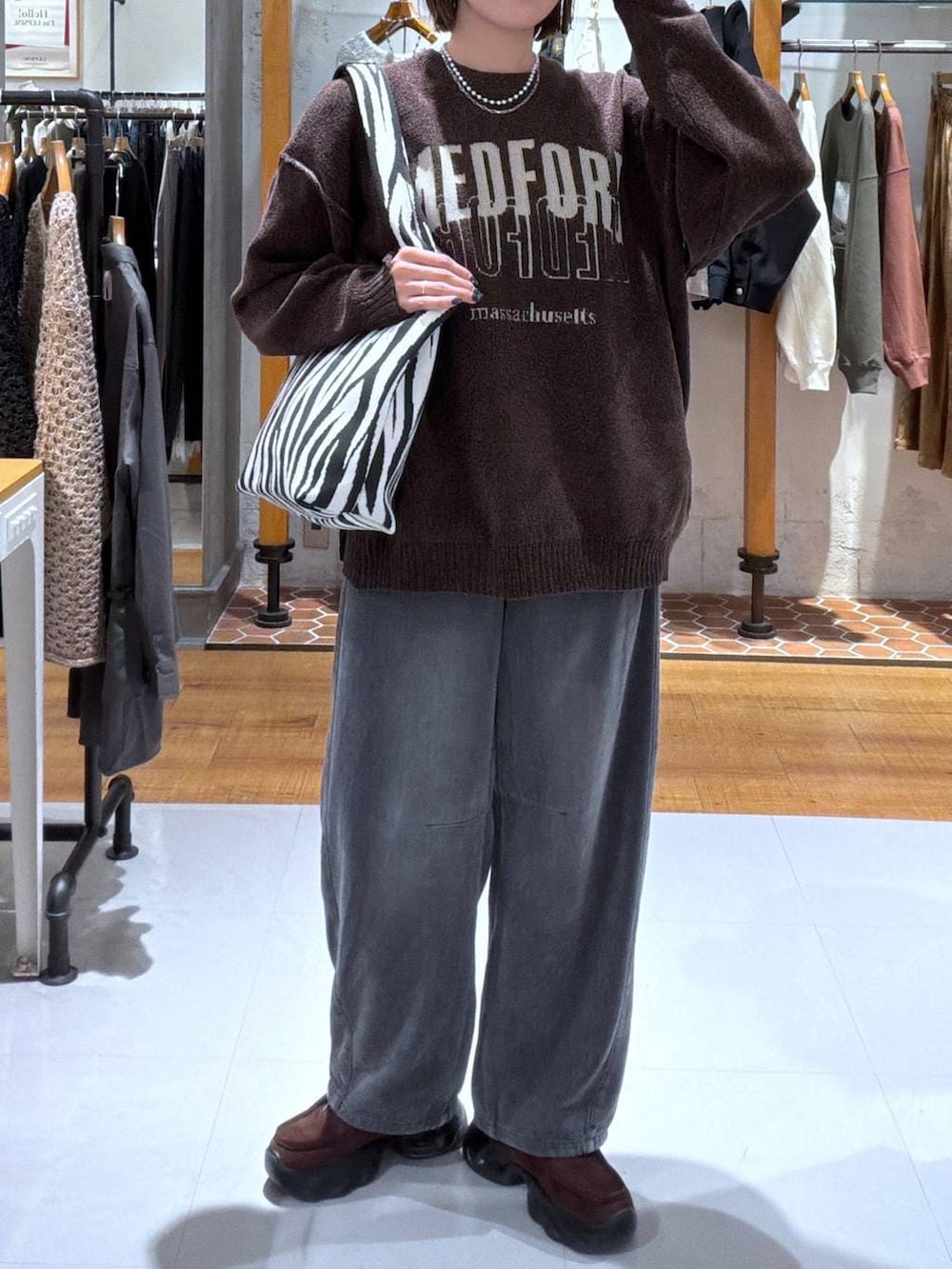 グレー系のデニムパンツ、その他のトートバッグ、ブラウン系のスニーカーを着用したレディースの秋コーディネートの2枚目の写真