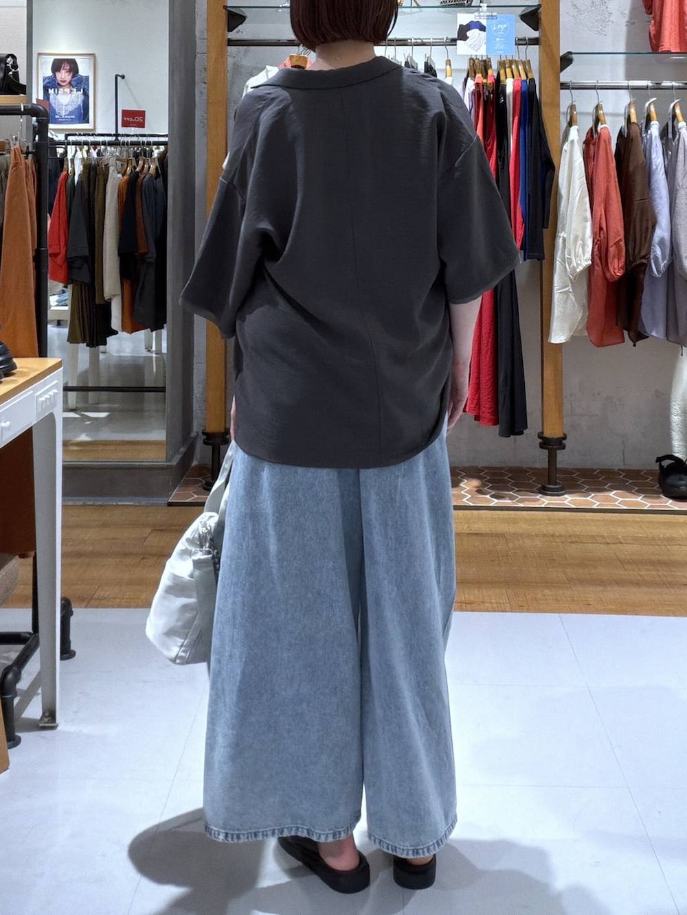 ブルー系のデニムパンツ、グレー系のショルダーバッグ、ブラック系のサンダルを着用したレディースの夏コーディネートの2枚目の写真