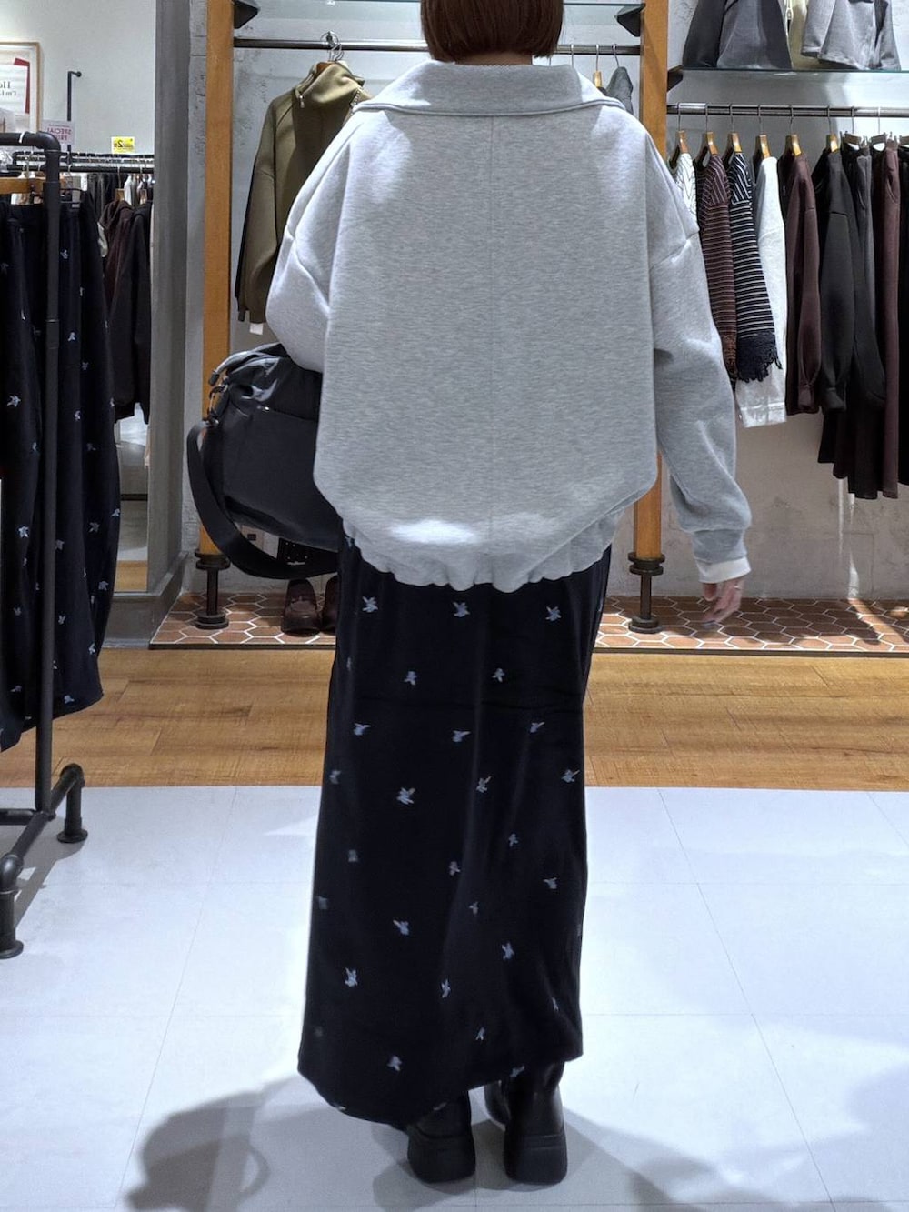 ブラック系のスカート、ブラック系のブーツ、ホワイト系のTシャツ/カットソーを着用したレディースの秋コーディネートの2枚目の写真