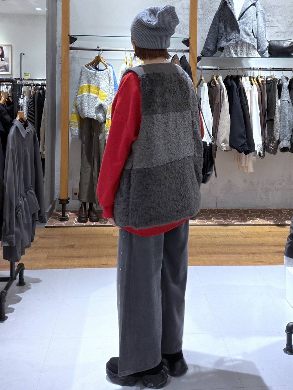 グレー系のデニムパンツ、ブラック系のスニーカー、レッド系のスウェットを着用したレディースの秋コーディネートの2枚目の写真