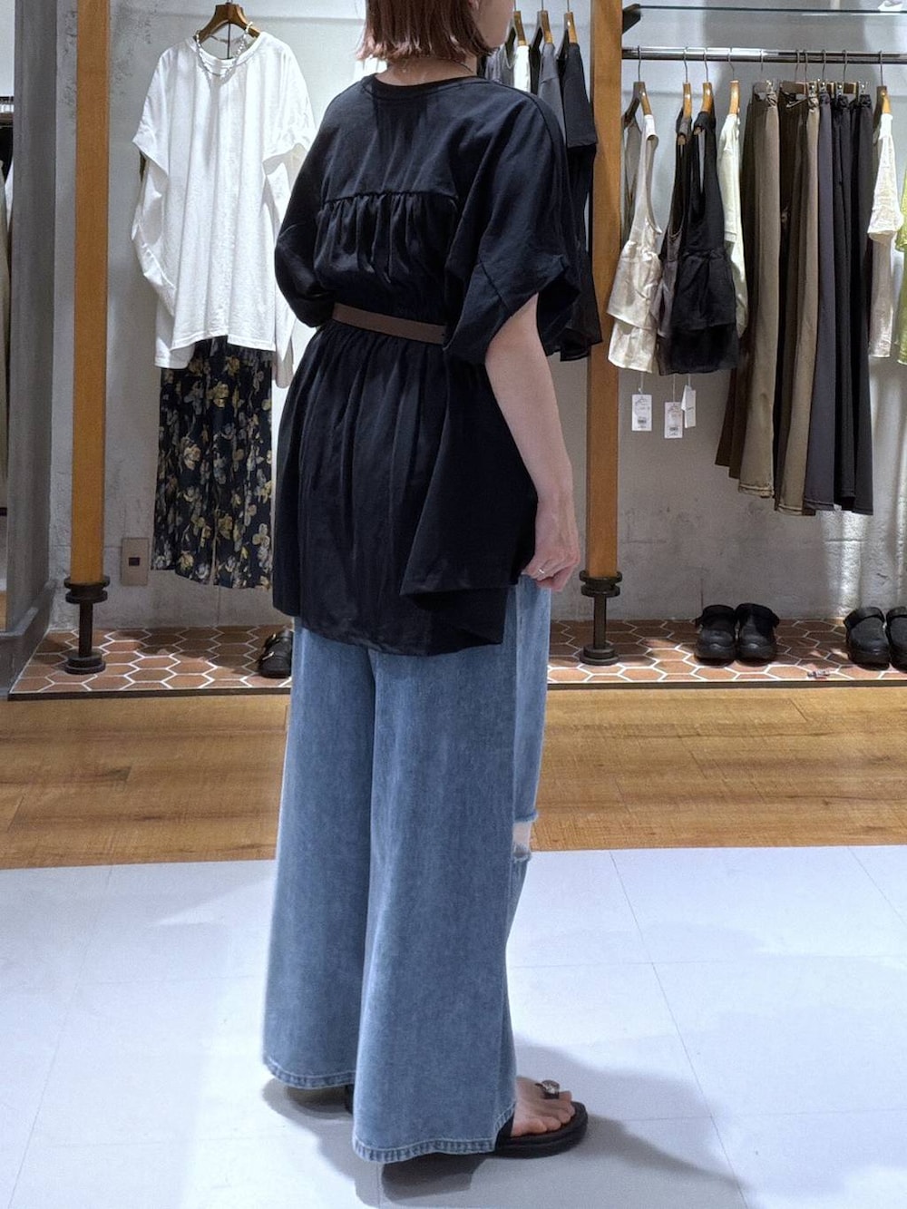 ブラック系のサンダル、ブラック系のTシャツ/カットソー、ブルー系のデニムパンツを着用したレディースの夏コーディネートの2枚目の写真