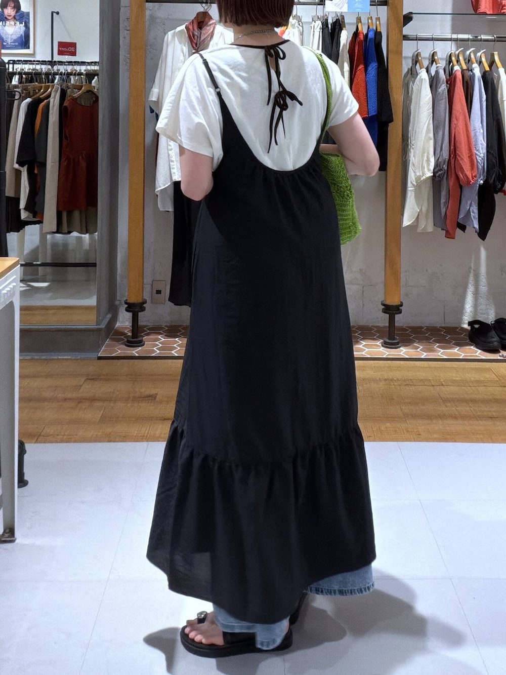 ブルー系のデニムパンツ、ブラック系のサンダル、グリーン系のショルダーバッグを着用したレディースの夏コーディネートの2枚目の写真