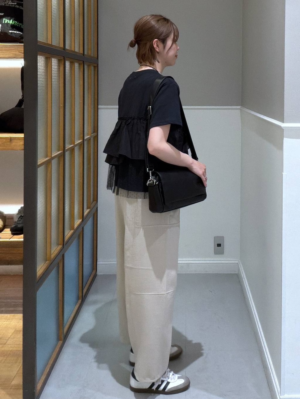 ブラック系のショルダーバッグ、ベージュ系のその他パンツ、ブラック系のTシャツ/カットソーを着用したレディースの春コーディネートの2枚目の写真