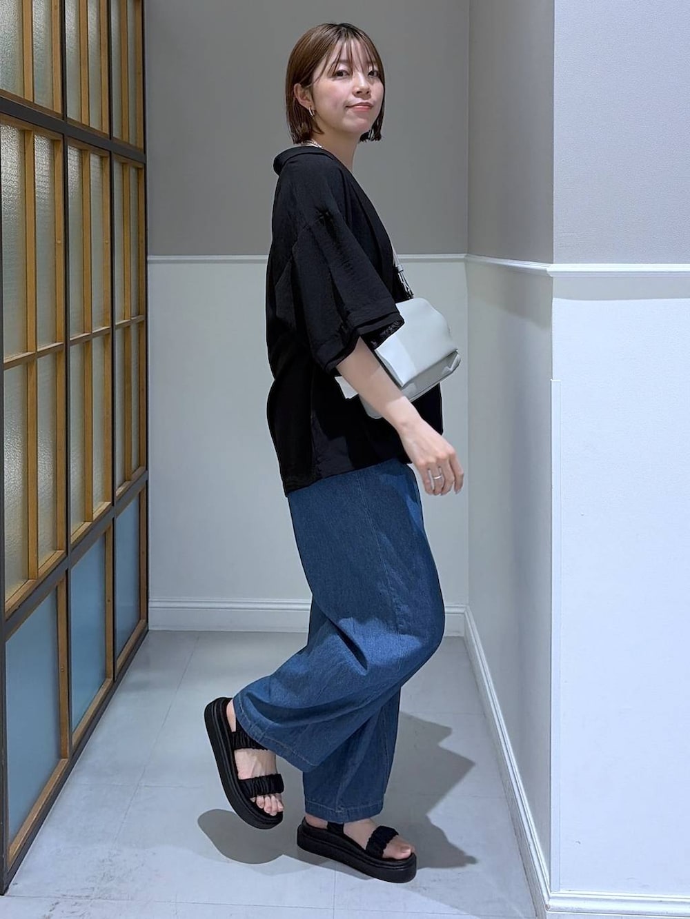 グレー系のショルダーバッグ、ブラック系のサンダル、ブラック系のテーラードジャケットを着用したレディースの春コーディネートの2枚目の写真