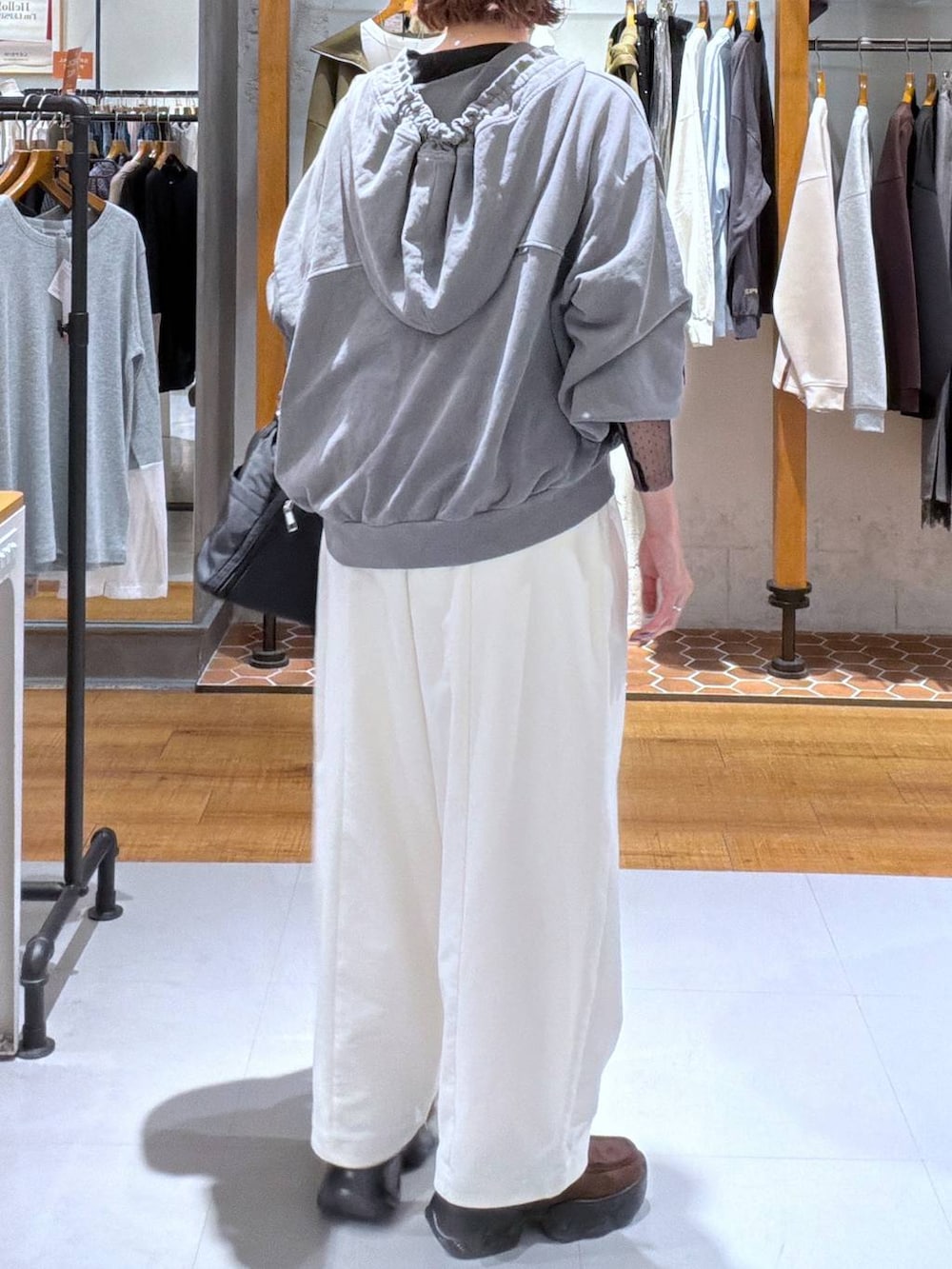 グレー系のパーカー、ブラウン系のスニーカー、ブラック系のTシャツ/カットソーを着用したレディースの秋コーディネートの2枚目の写真