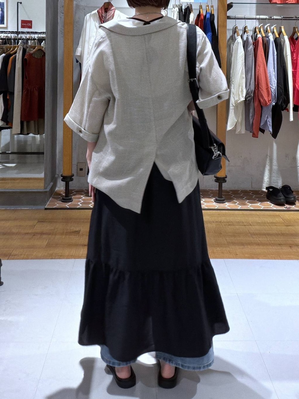 ブラック系のショルダーバッグ、ブルー系のデニムパンツ、ブラック系のサンダルを着用したレディースの夏コーディネートの2枚目の写真