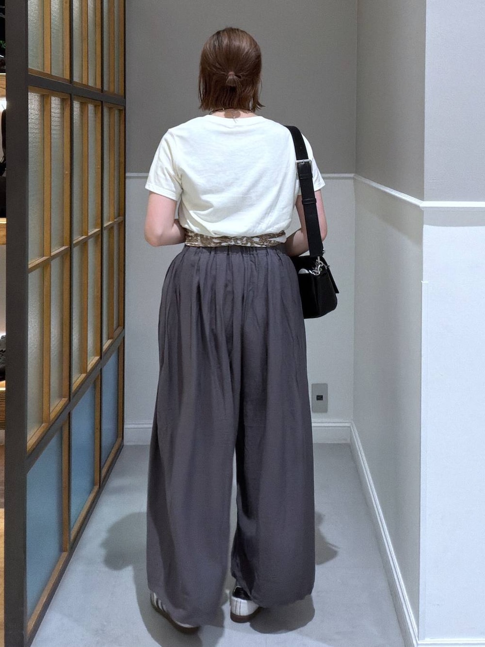 ブラック系のショルダーバッグ、グレー系のその他パンツ、ホワイト系のTシャツ/カットソーを着用したレディースの春コーディネートの2枚目の写真