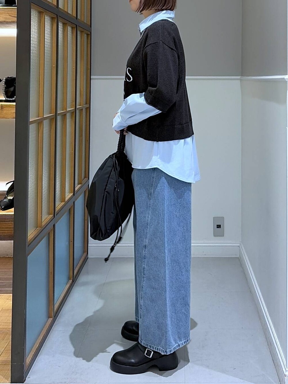 ブラック系のサンダル、ブラック系のトートバッグ、ブルー系のデニムパンツを着用したレディースの冬コーディネートの2枚目の写真