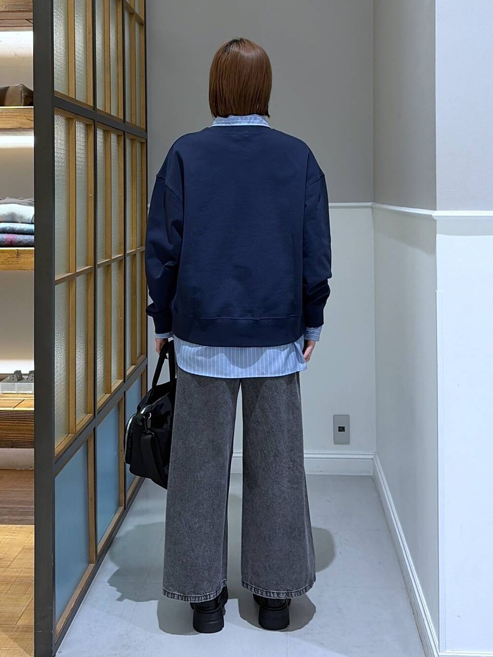 グレー系のデニムパンツ、ブルー系のシャツ/ブラウス、ブラック系のトートバッグを着用したレディースの冬コーディネートの2枚目の写真