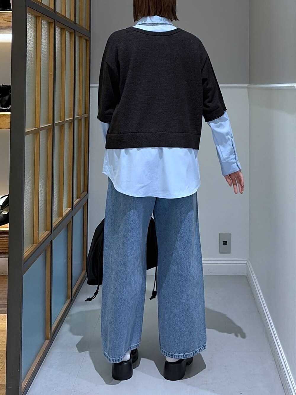 ブラック系のサンダル、ブラック系のトートバッグ、ブルー系のデニムパンツを着用したレディースの冬コーディネートの3枚目の写真