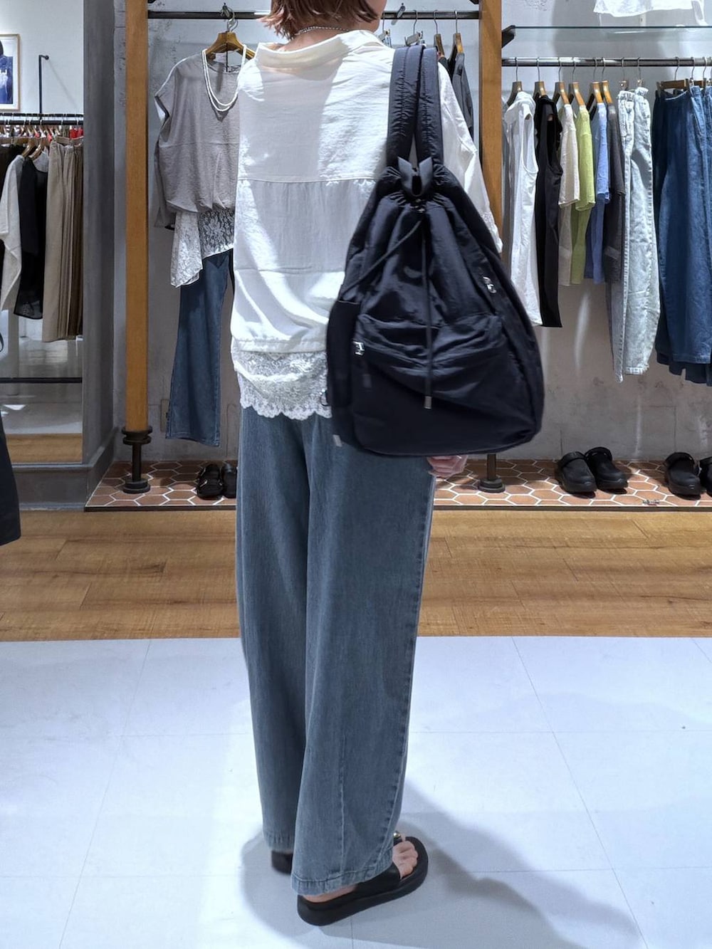ブラック系のサンダル、ブルー系のデニムパンツ、ブラック系のタンクトップを着用したレディースの夏コーディネートの2枚目の写真