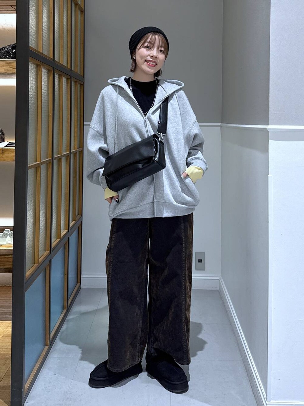 ブラック系のニット/セーター、ブラック系のショルダーバッグ、グレー系のパーカーを着用したレディースの冬コーディネートの3枚目の写真