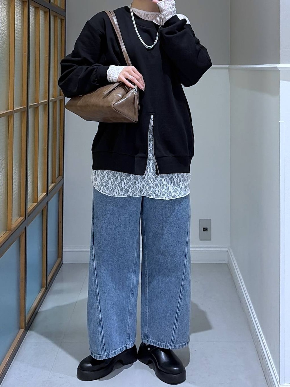 ブラック系のサンダル、ブラウン系のボストンバッグ、ブルー系のデニムパンツを着用したレディースの冬コーディネートの2枚目の写真