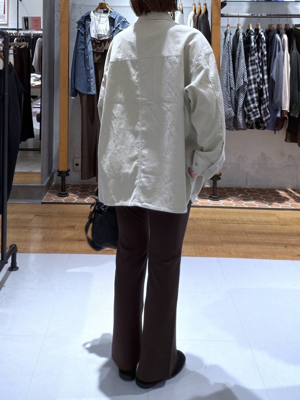 ブラック系のパンプス、ブラック系のトートバッグ、ベージュ系のシャツ/ブラウスを着用したレディースの秋コーディネートの2枚目の写真
