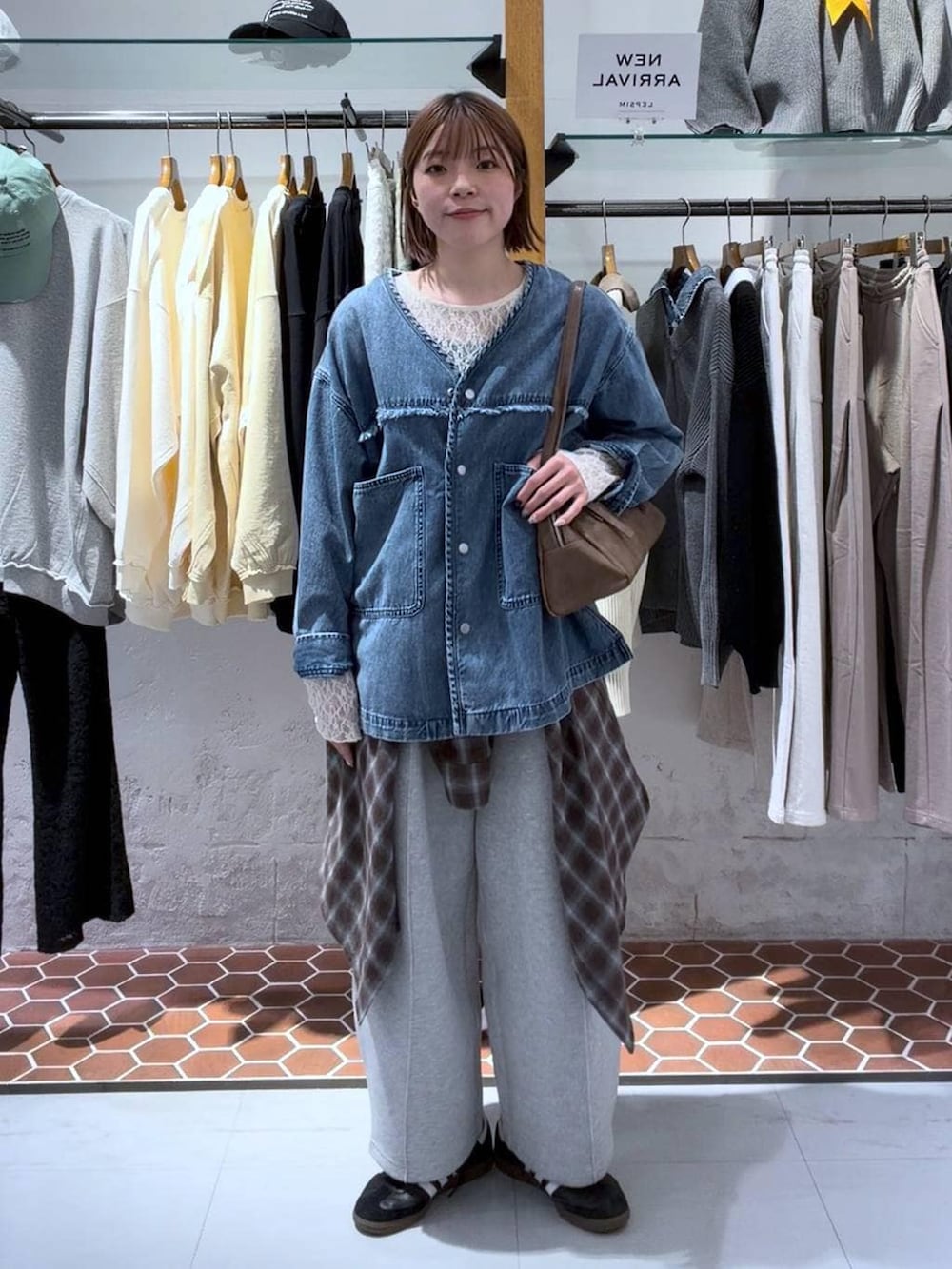 グレー系のスウェットパンツ、ブラウン系のボストンバッグ、ホワイト系のTシャツ/カットソーを着用したレディースの冬コーディネートの3枚目の写真