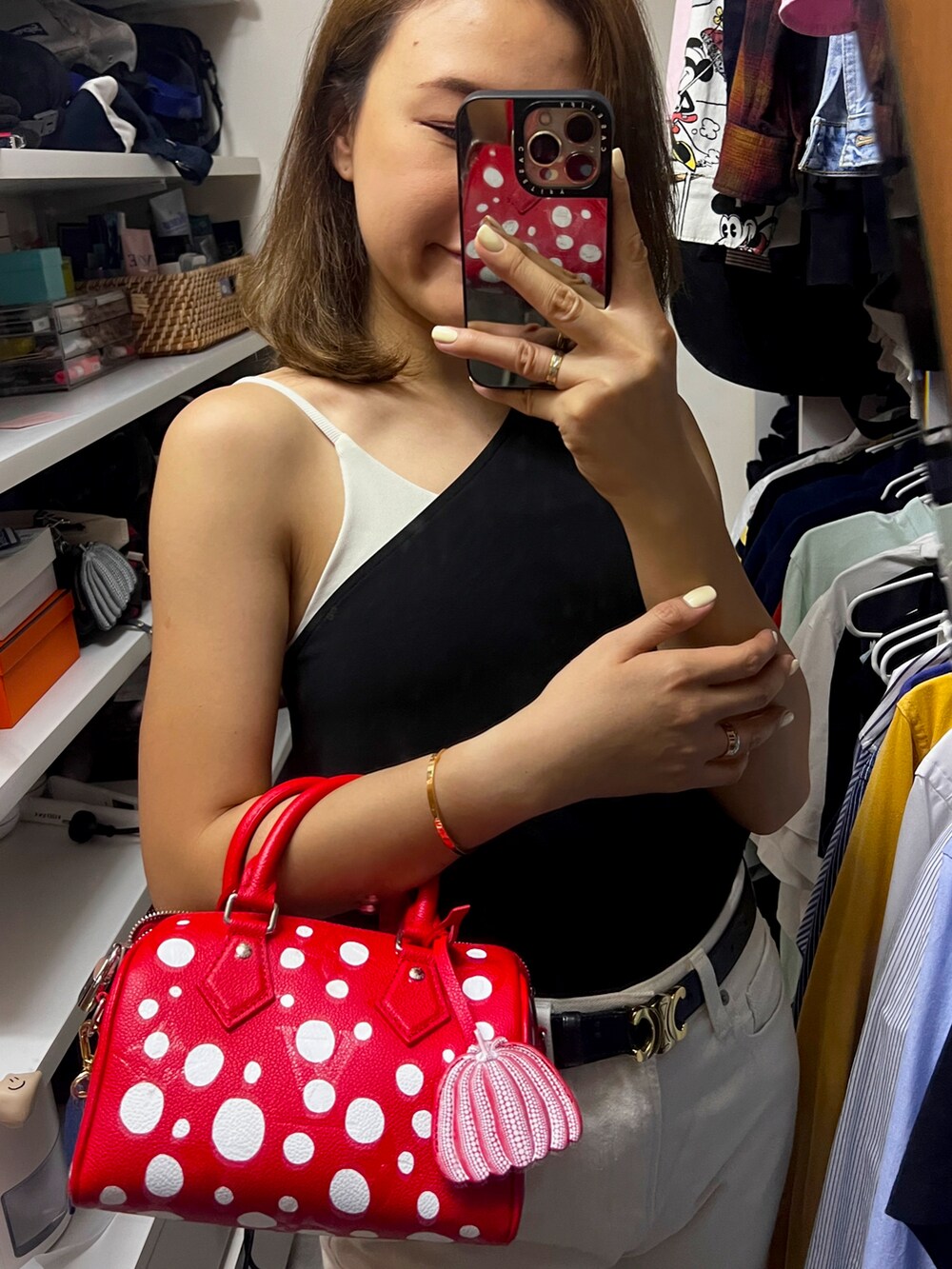 ブラック系のタンクトップ、レッド系のハンドバッグ、ホワイト系のデニムパンツを着用したレディースの夏コーディネートの2枚目の写真