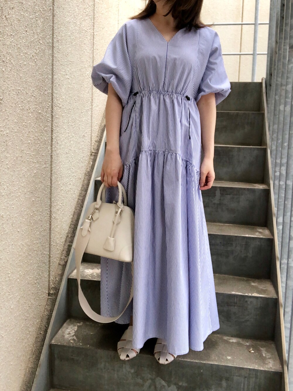 ブルー系のワンピース、ホワイト系のボストンバッグ、ホワイト系のサンダルを着用したレディースの春コーディネートの4枚目の写真