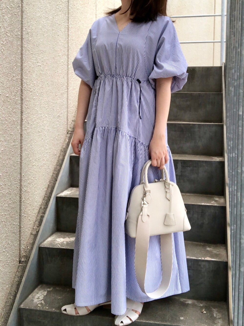 ブルー系のワンピース、ホワイト系のボストンバッグ、ホワイト系のサンダルを着用したレディースの春コーディネートの3枚目の写真