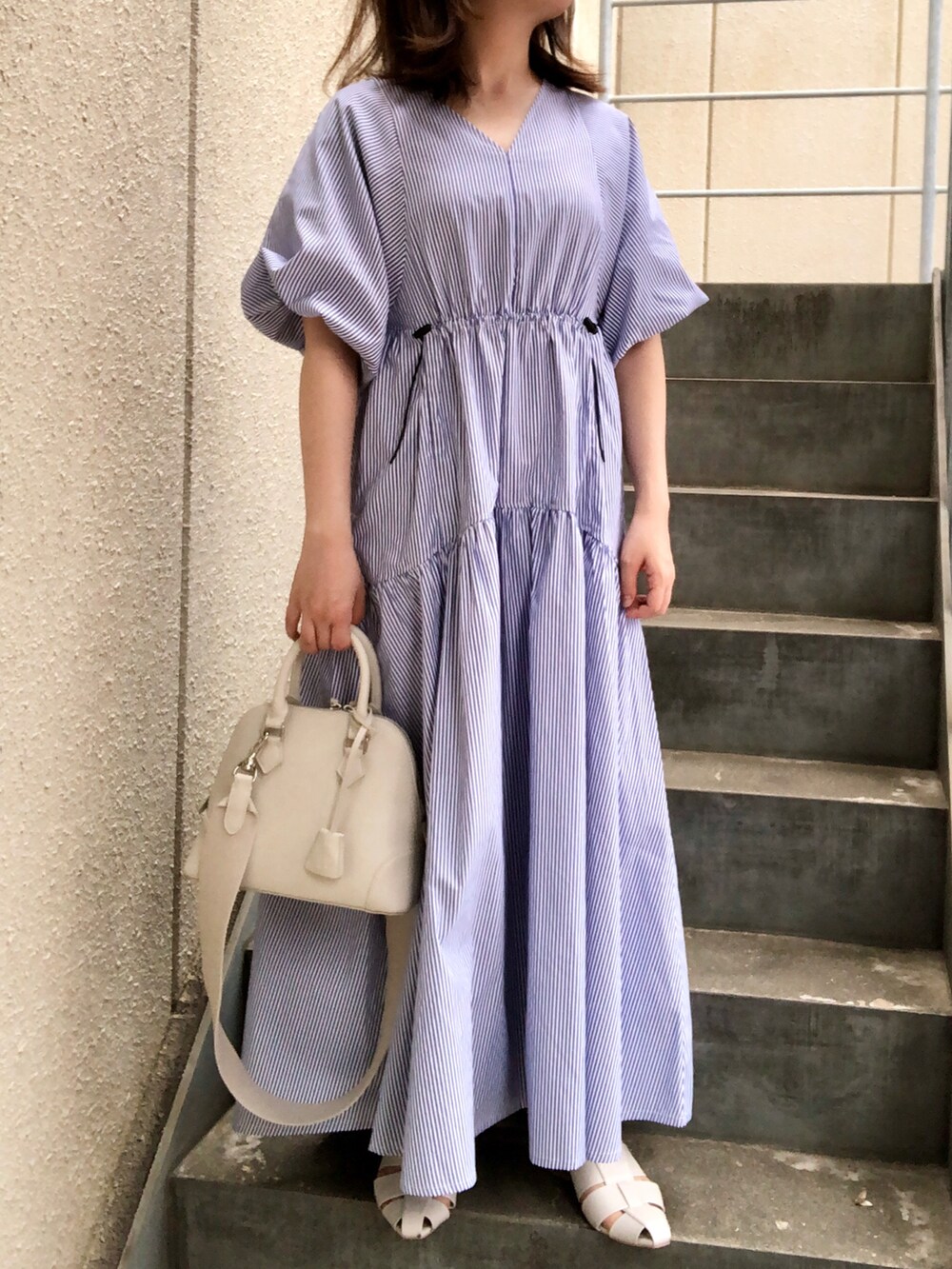 ブルー系のワンピース、ホワイト系のボストンバッグ、ホワイト系のサンダルを着用したレディースの春コーディネートの2枚目の写真