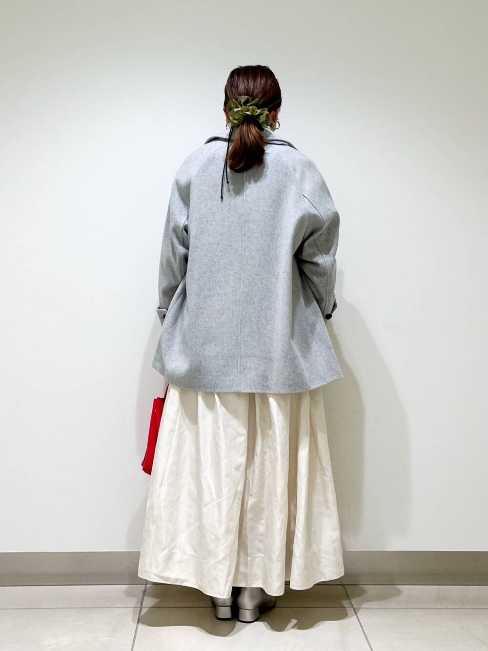 グレー系のピーコート、レッド系のトートバッグ、ホワイト系のニット/セーターを着用したレディースの秋コーディネートの3枚目の写真