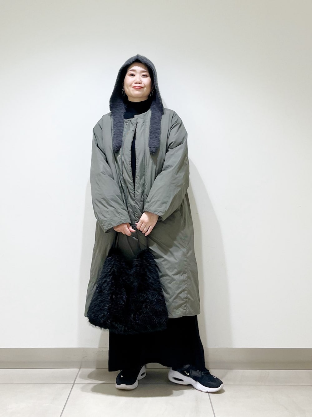 グリーン系のその他アウター、ブラック系のワンピース、ブラック系のハンドバッグを着用したレディースの冬コーディネートの5枚目の写真