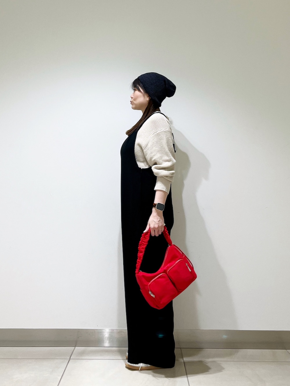 ブラック系のサロペット/オーバーオール、ベージュ系のニット/セーター、ブラウン系のショルダーバッグを着用したレディースの春コーディネートの2枚目の写真