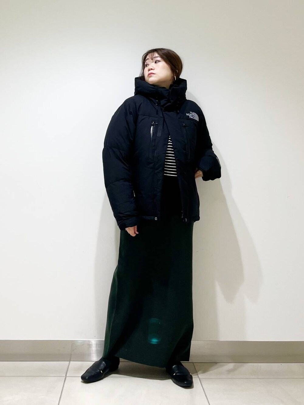 ブラック系のローファー、ブラック系のTシャツ/カットソー、グリーン系のスカートを着用したレディースの冬コーディネートの2枚目の写真