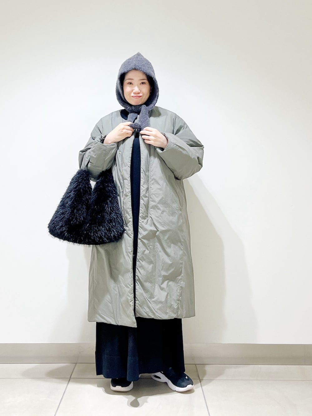 グリーン系のその他アウター、ブラック系のワンピース、ブラック系のハンドバッグを着用したレディースの冬コーディネートの4枚目の写真