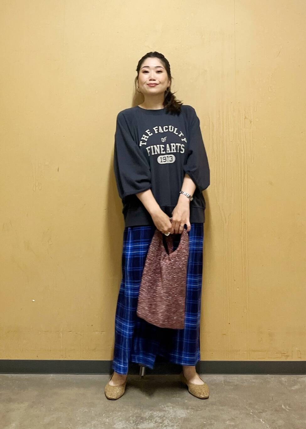 ブルー系のスカート、ベージュ系のパンプス、ブラック系のTシャツ/カットソーを着用したレディースの夏コーディネートの6枚目の写真