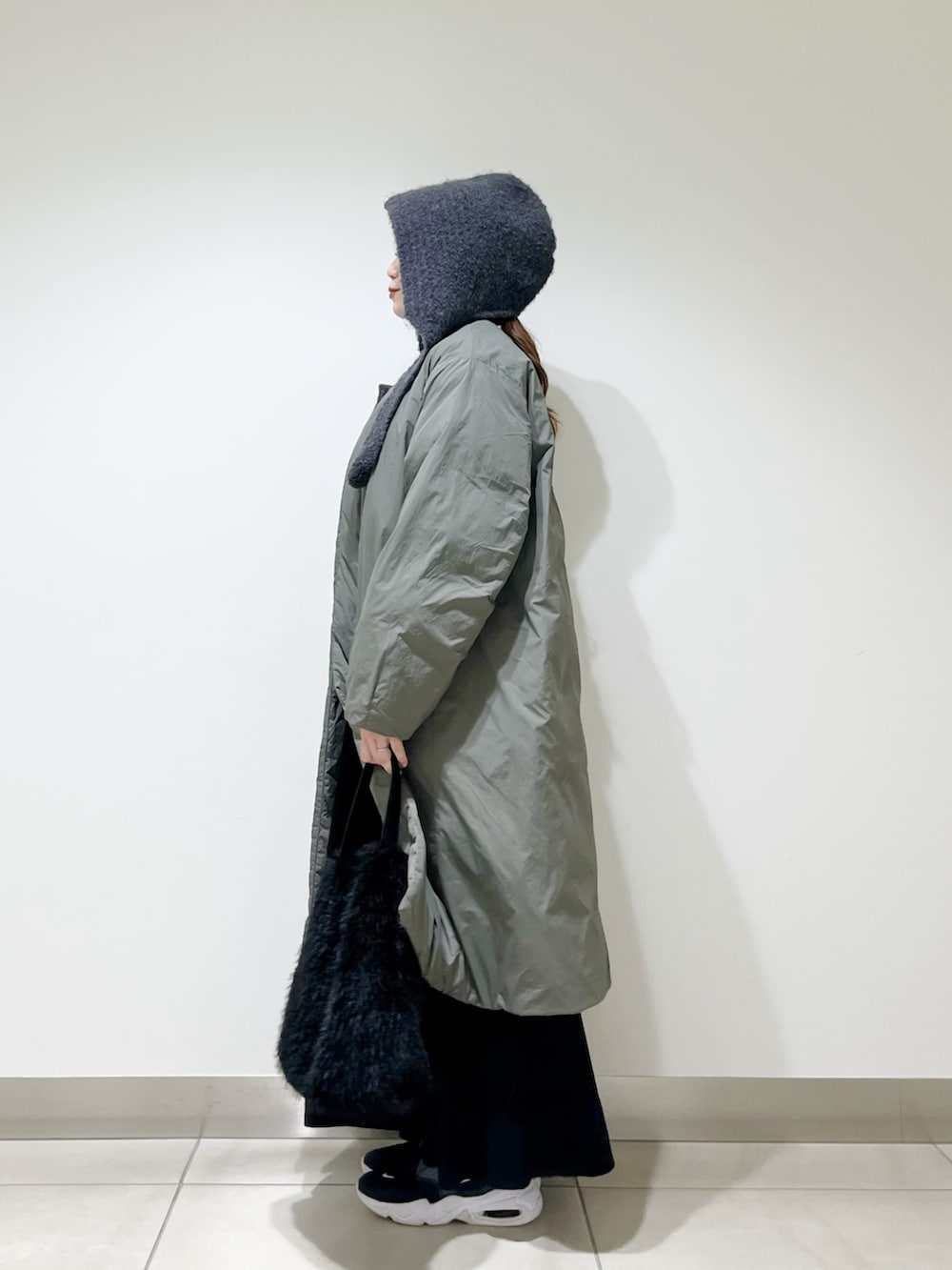 グリーン系のその他アウター、ブラック系のワンピース、ブラック系のハンドバッグを着用したレディースの冬コーディネートの2枚目の写真