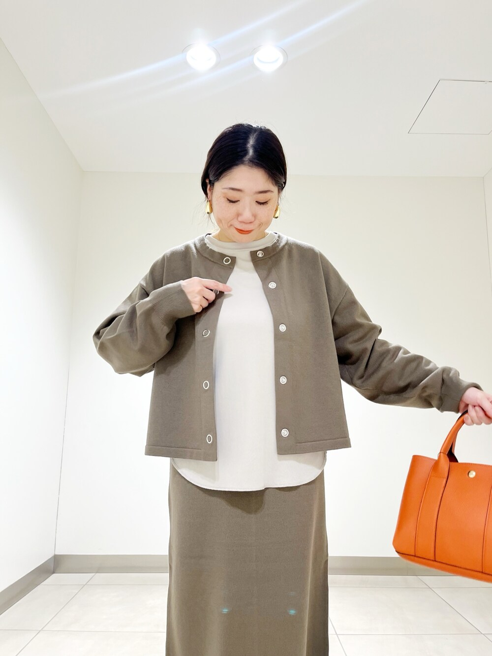 ベージュ系のTシャツ/カットソー、ブラウン系のカーディガン/ボレロ、ブラウン系のスカートを着用したレディースの秋コーディネートの2枚目の写真