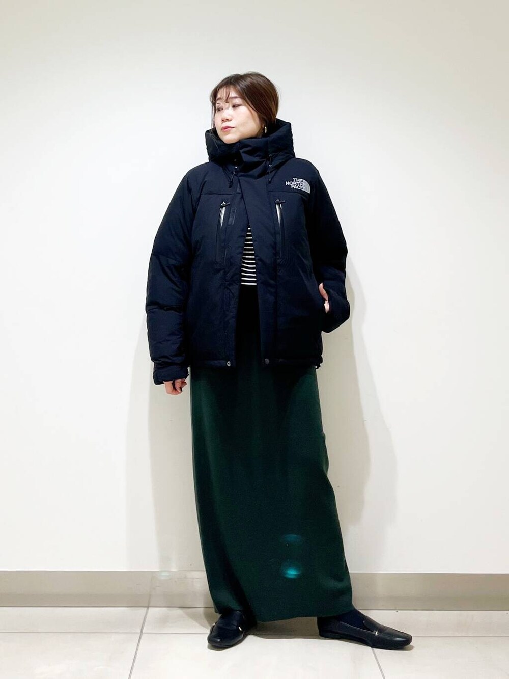 ブラック系のローファー、ブラック系のTシャツ/カットソー、グリーン系のスカートを着用したレディースの冬コーディネートの5枚目の写真