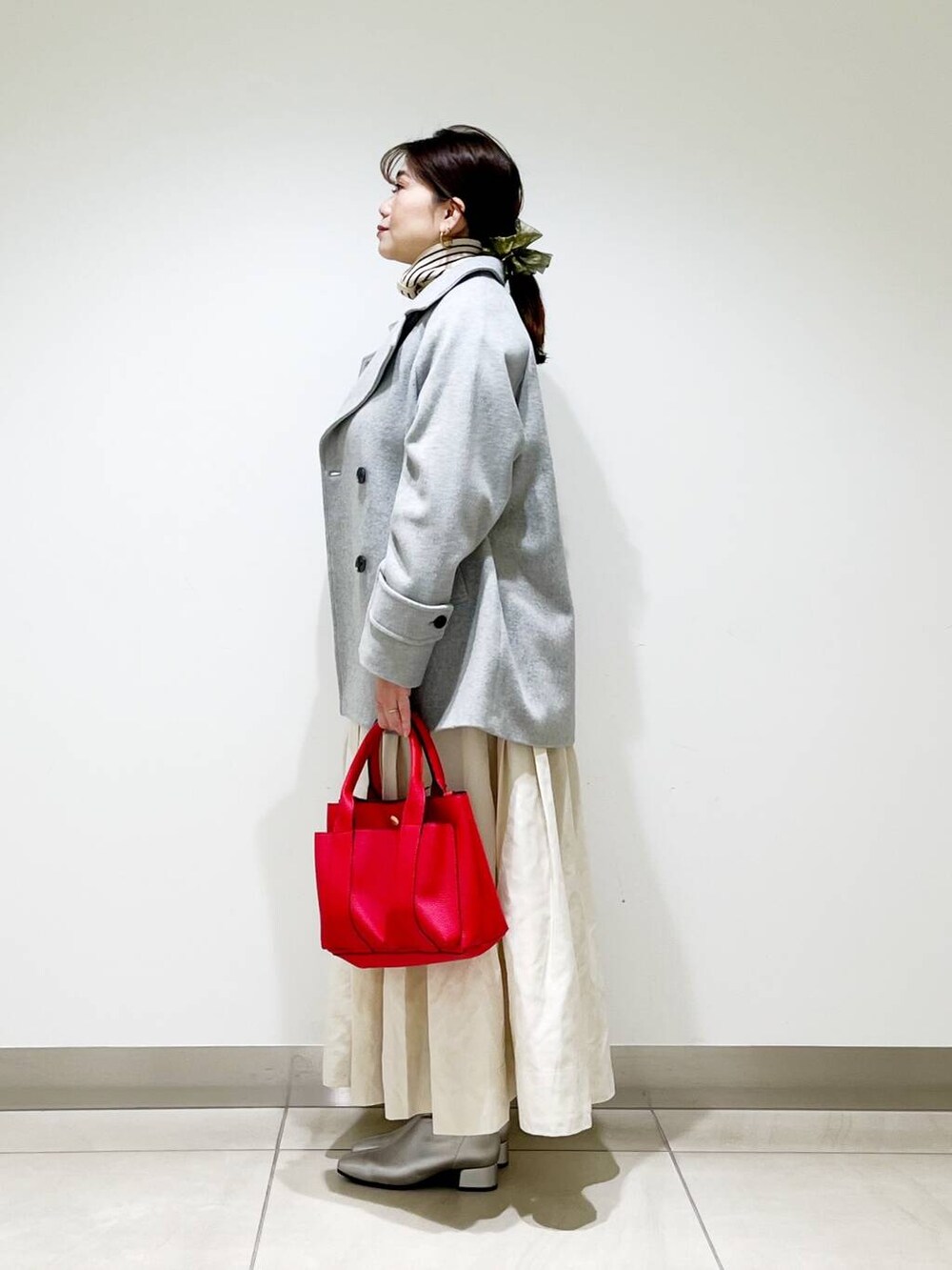 グレー系のピーコート、レッド系のトートバッグ、ホワイト系のニット/セーターを着用したレディースの秋コーディネートの4枚目の写真
