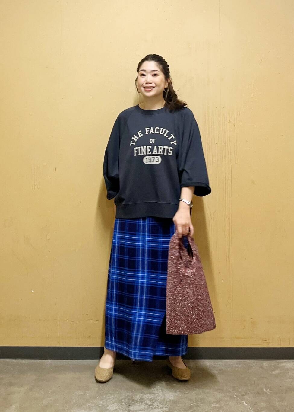 ブルー系のスカート、ベージュ系のパンプス、ブラック系のTシャツ/カットソーを着用したレディースの夏コーディネートの2枚目の写真