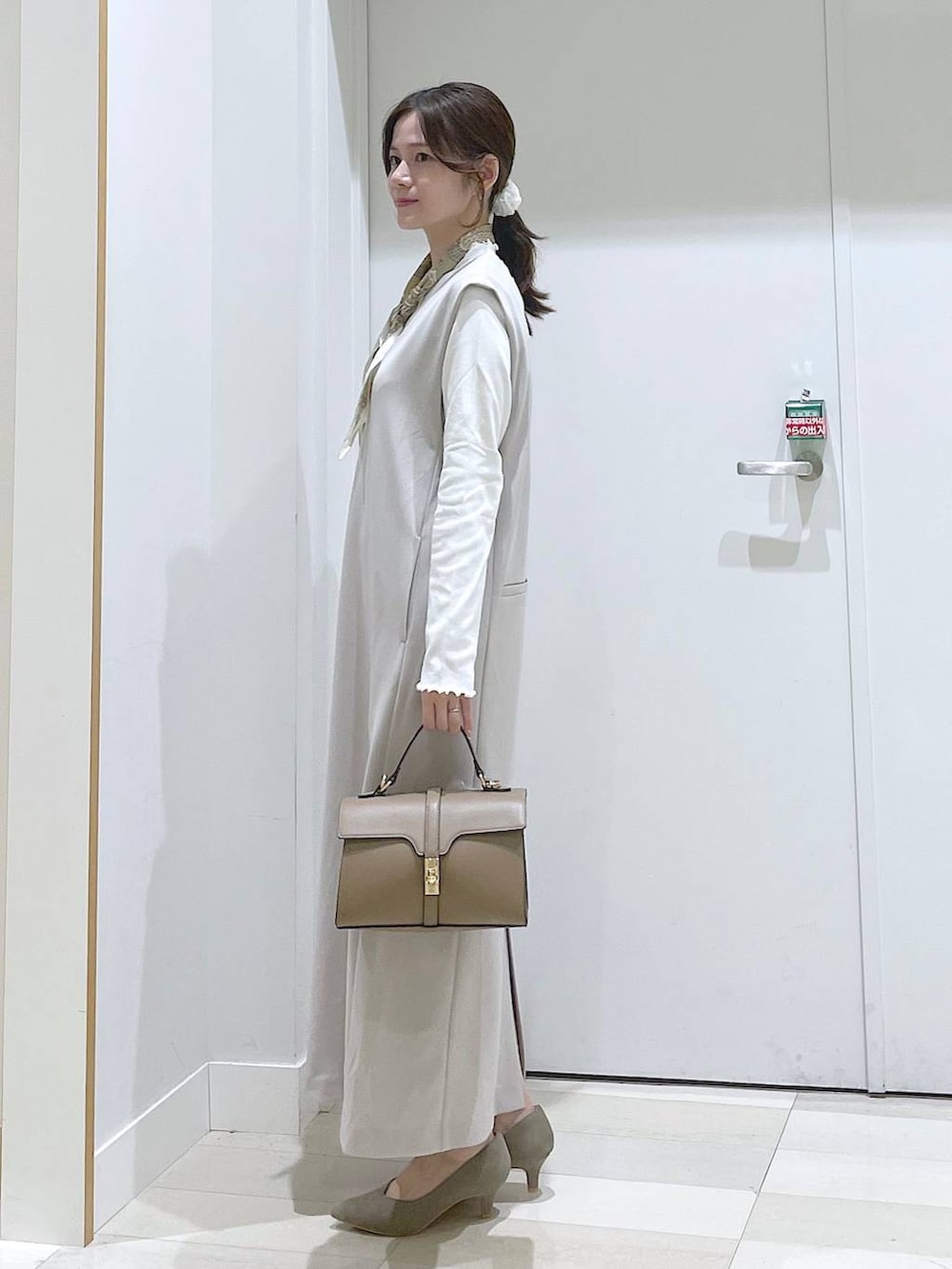 グレー系のジャンパースカート、ベージュ系のショルダーバッグ、ベージュ系のパンプスを着用したレディースの春コーディネートの2枚目の写真