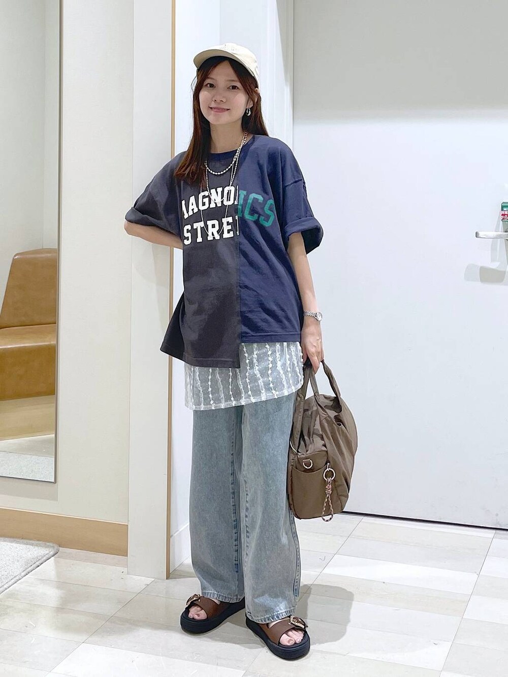 ブルー系のデニムパンツ、ブラウン系のサンダル、ベージュ系のその他小物を着用したレディースの夏コーディネートの4枚目の写真