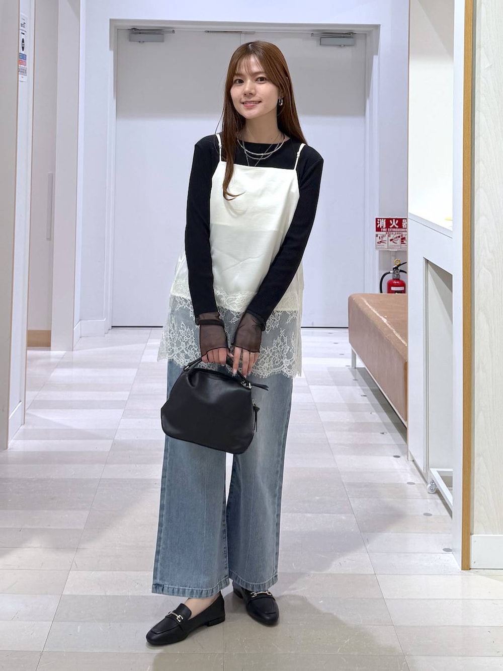 ブラック系のローファー、ブラック系のショルダーバッグ、ブルー系のデニムパンツを着用したレディースの春コーディネートの4枚目の写真