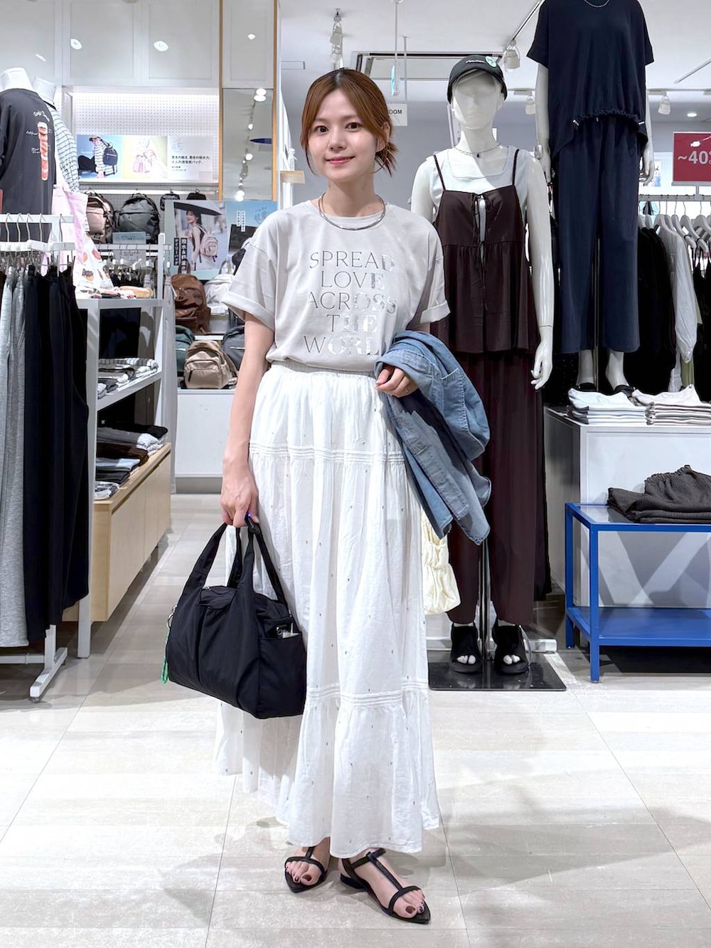 ブラック系のトートバッグ、ホワイト系のスカート、ベージュ系のTシャツ/カットソーを着用したレディースの夏コーディネートの5枚目の写真