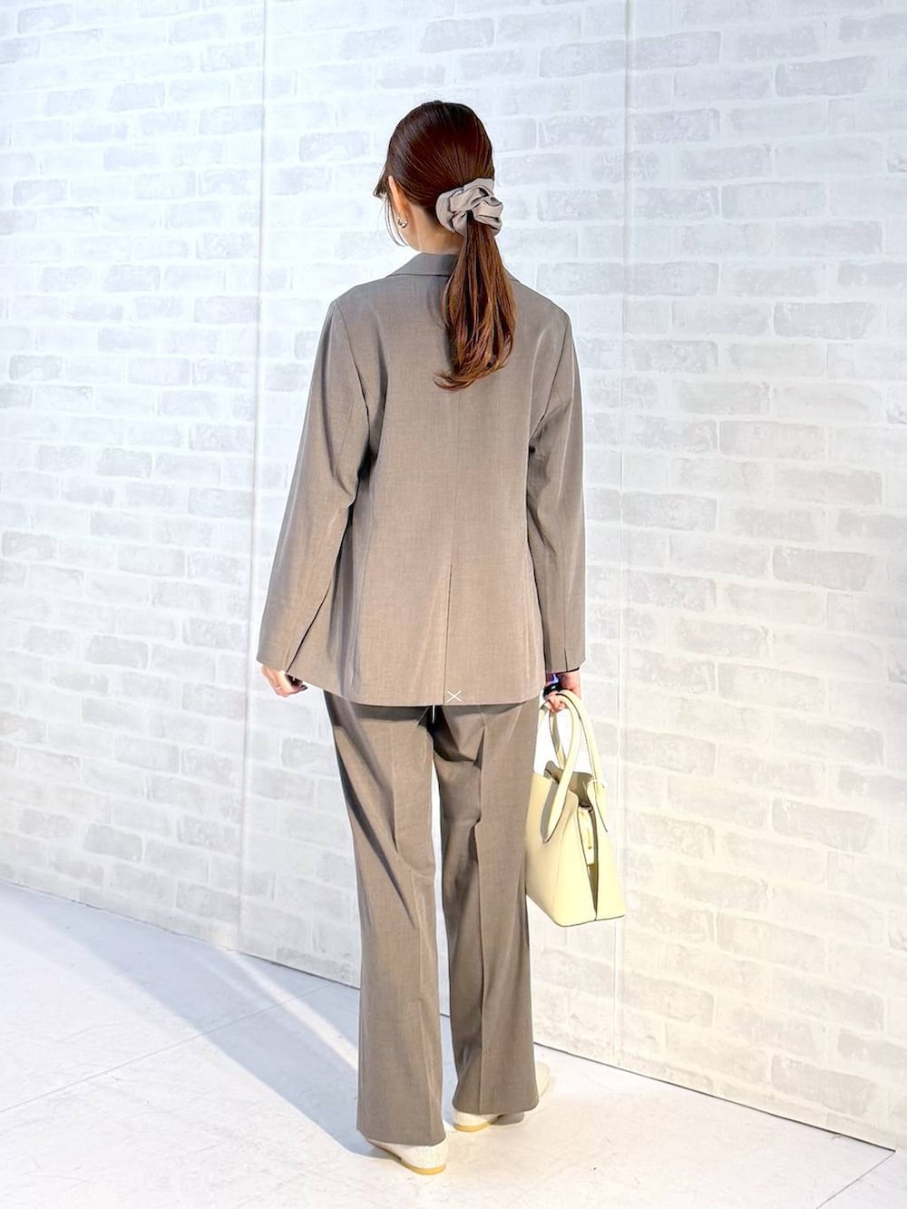 ベージュ系のパンプス、ホワイト系のショルダーバッグ、ブラウン系のスラックスを着用したレディースの冬コーディネートの3枚目の写真