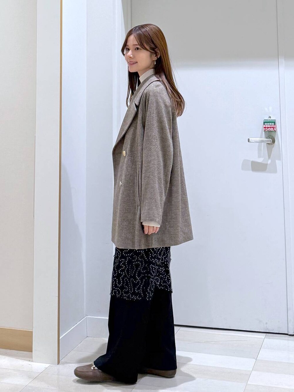 ブラウン系のチェスターコート、ブラック系のその他パンツ、ホワイト系のニット/セーターを着用したレディースの秋コーディネートの2枚目の写真