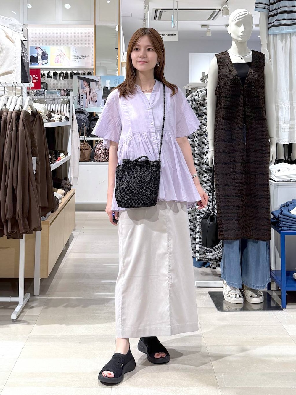ベージュ系のスカート、ホワイト系のタンクトップ、ブラック系のクラッチバッグを着用したレディースの夏コーディネートの4枚目の写真